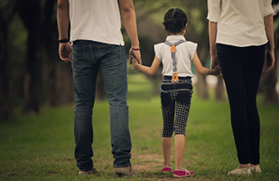 Image of a man and woman walking while holding a child's hands