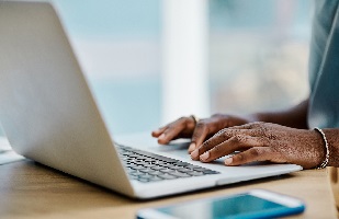 Black woman typing on a laptop computer.