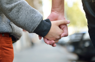 Image of a child and adult holding hands.