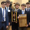 Image showing 10 young men, all wearing suits, one man is holding a trophy and another is holding a plaque.
