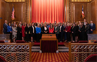 Image showing a large group of men and women standing at the front of the courtroom of the Thomas J. Moyer Ohio Judicial Center.