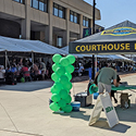 A row of canopied booths set up along the side of a multi-story building in a parking lot.