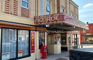 A red marquee with gold lettering on a historic theater building.