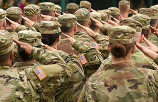 Image showing two rows of military soldiers wearing green, camouflage fatigues, all soluting.