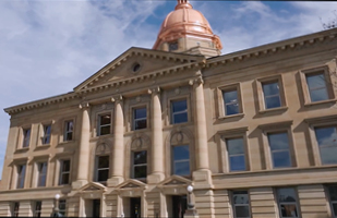 A multi-story building with columns in front and a cupola on the roof.
