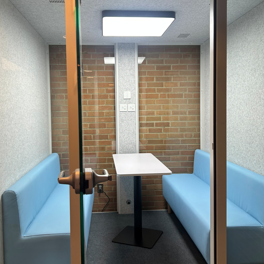 a small room with a table and two booth benches with glass windows and doors