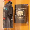 A black t-shirt on display in a plexiglass case.