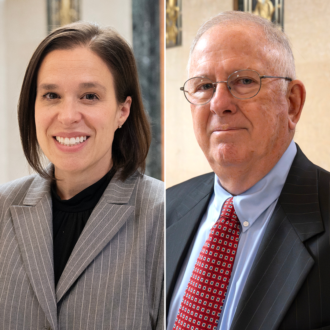 A woman speaking at a podiem with the US flag and Ohio flag in the background with a table of women listening to the speaker