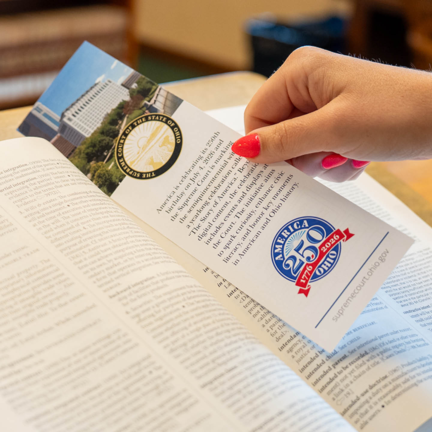 A hand putting a bookmark into a book with the seal of the Supreme Court of Ohio