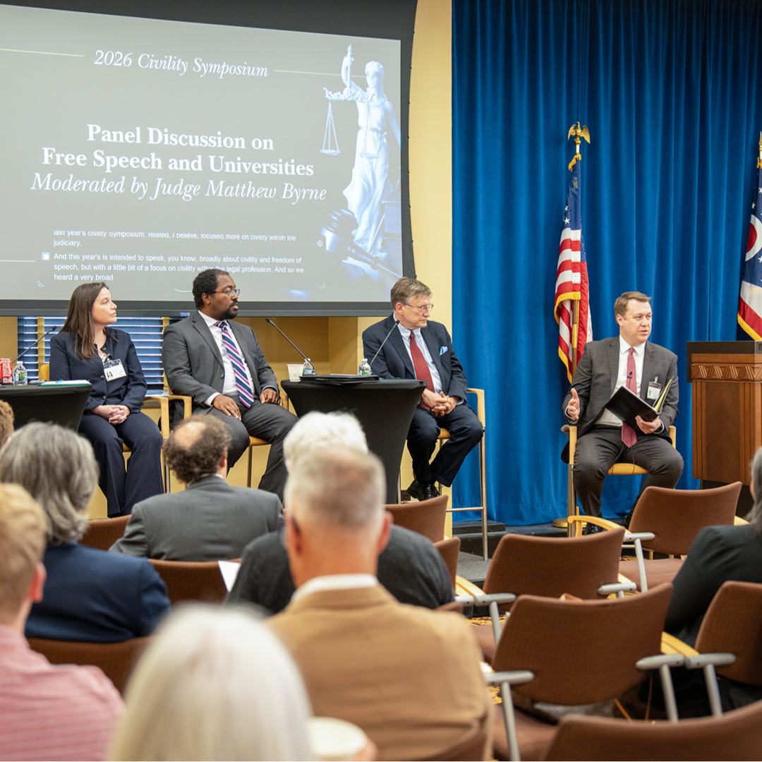 A pannel of speakers on the stage with an audience watching