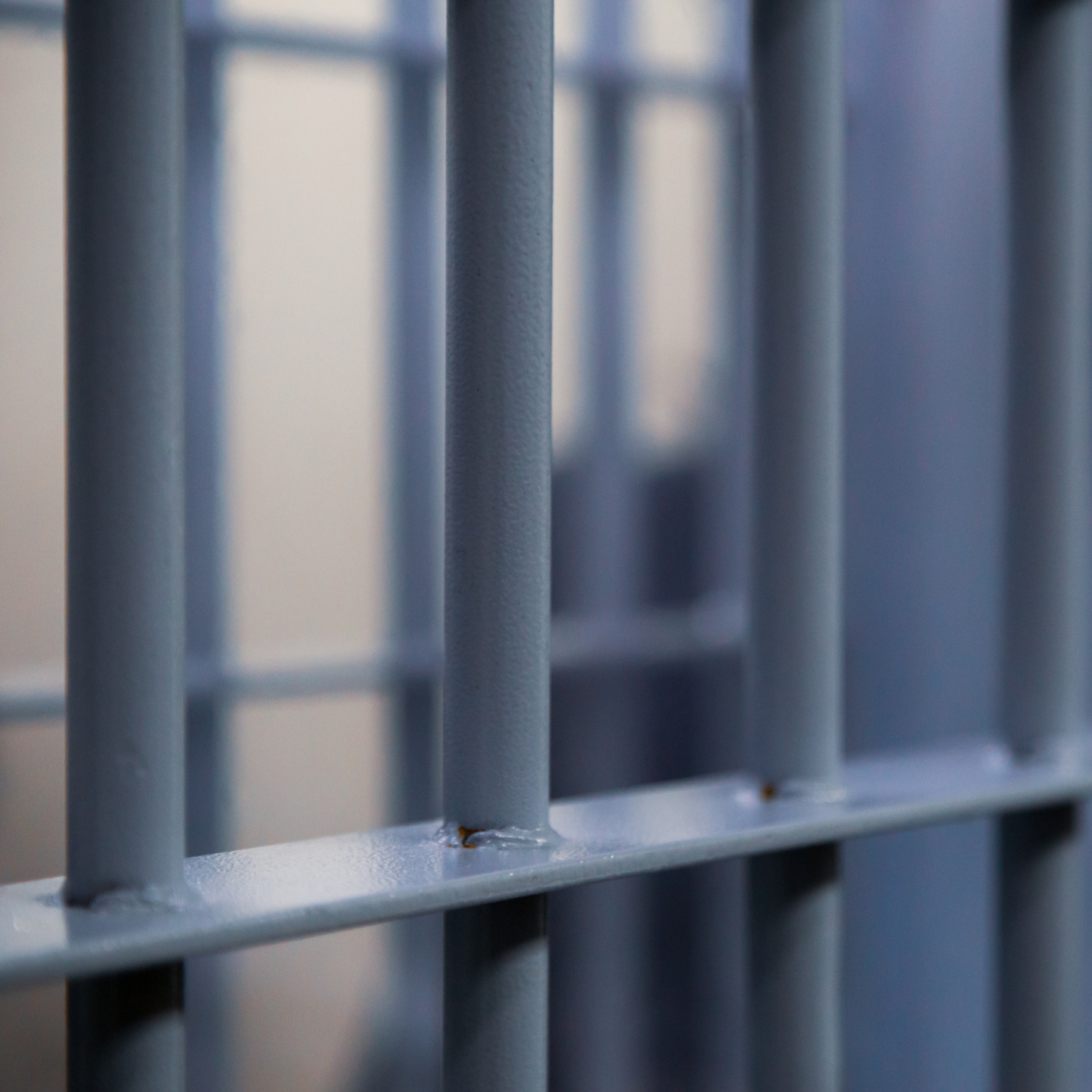 Close-up of gray metal railing bars with visible welds and a blurred background.