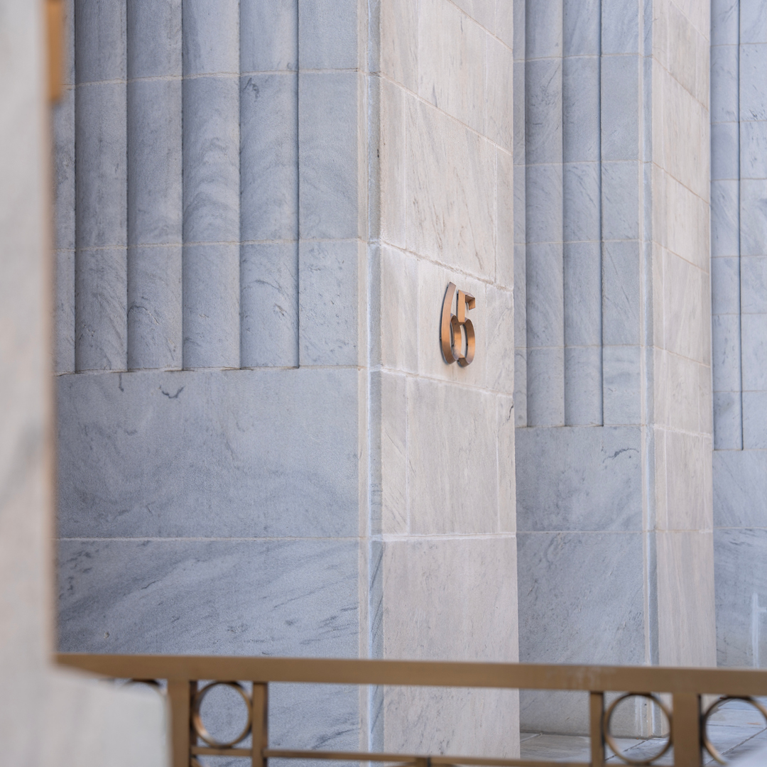 The exterior of a marble building with a sign reading '65'