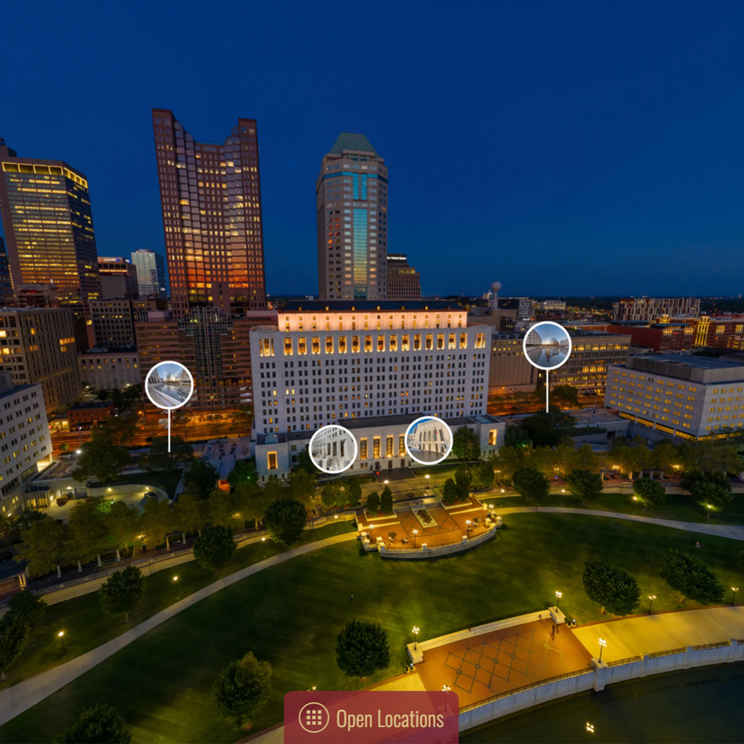 Aerial view of a cityscape at dusk, featuring illuminated skyscrapers and a prominent government building.