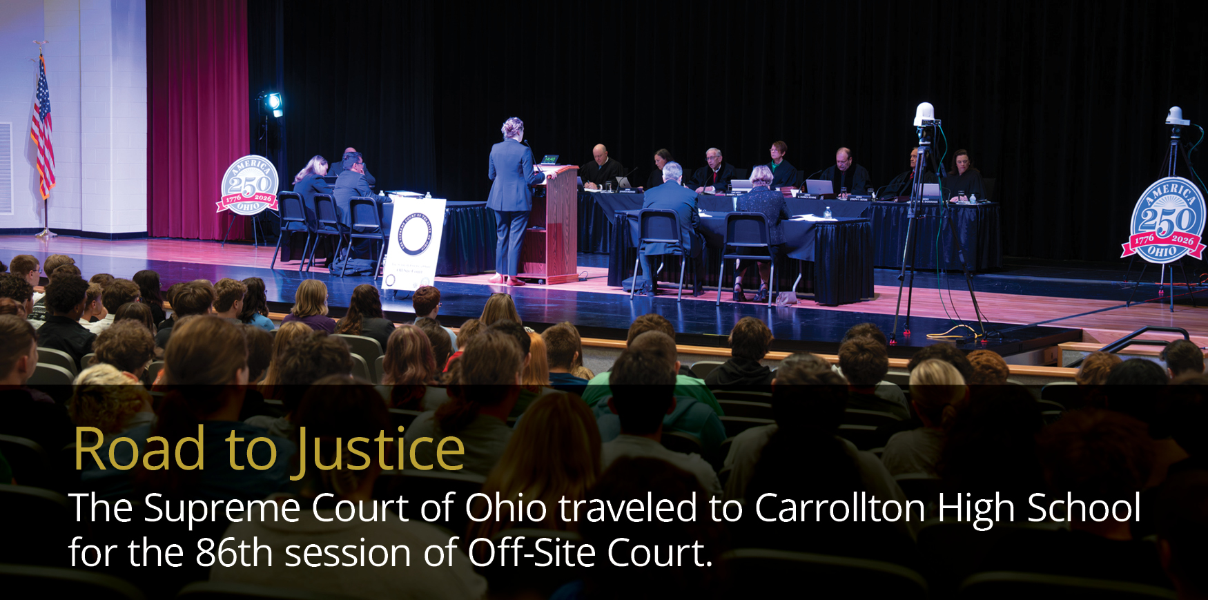 Audience watches Ohio Supreme Court justices at a table on stage in a high school auditorium, with the caption 'Road to Justice' visible.