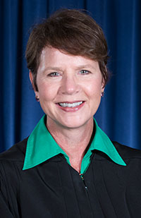 Image of a female judge wearing a black judicial robe and a green blouse.