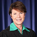 Image of a female judge wearing a black judicial robe and a green blouse.