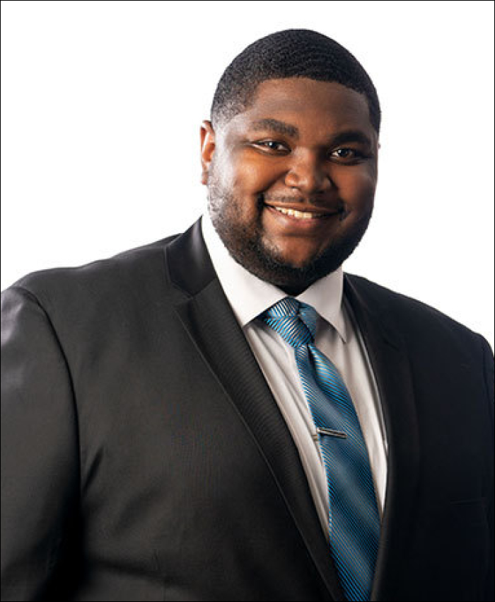 Image of a smiling man wearing a black suit