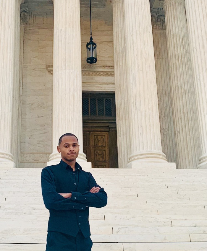 Image of a man standing in front of a building with large marble columns