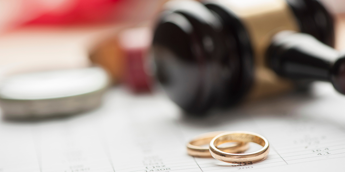 Image of a pair of gold wedding bands sitting in front of a wooden gavel
