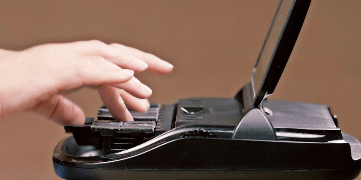 Hands typing on a stenotype machine.