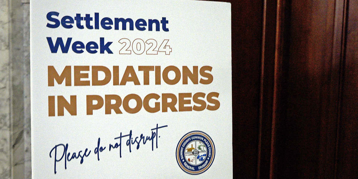 A large, white sign that reads: 'Settlement Week 2024 Mediations in Progress. Please do not disrupt.'