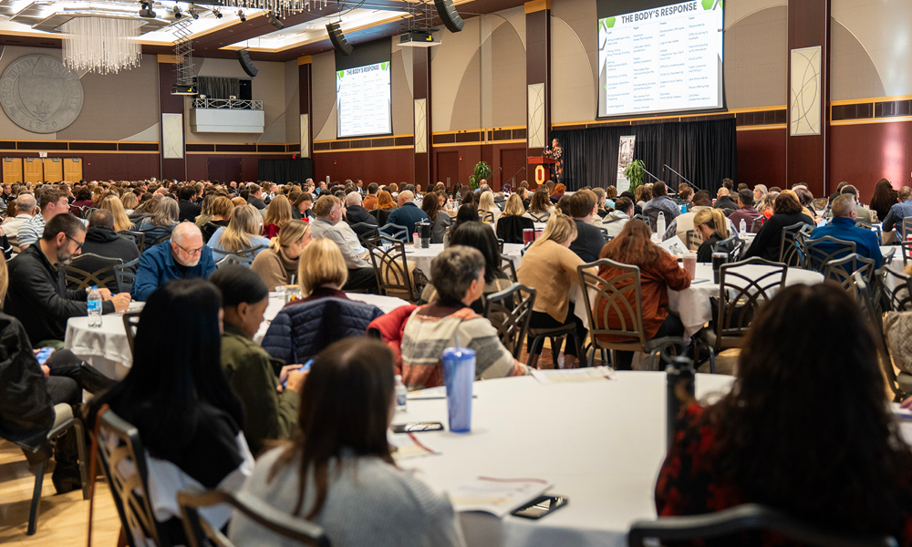 A large group of men and women seated at round tables.