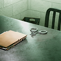 Image of a silver, metal table with some brown fole folders and handcuff on top.